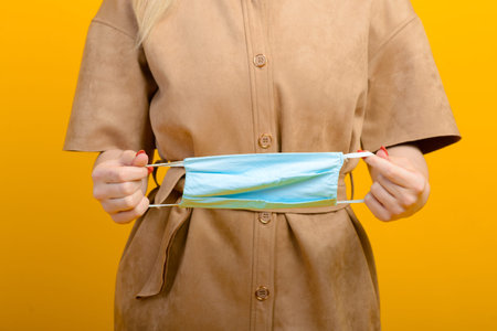 Image of female hands with blue mask on yellow background Healthcare Covid 19 outbreak