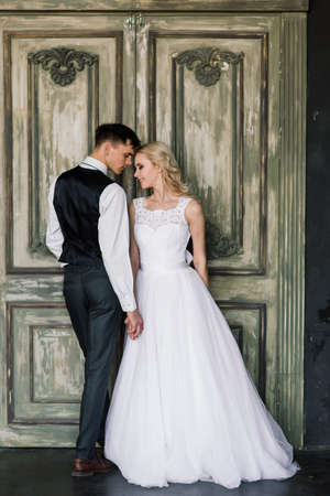 Cute wedding couple in the interior of a classic studio. They kiss and hug each other.の写真素材