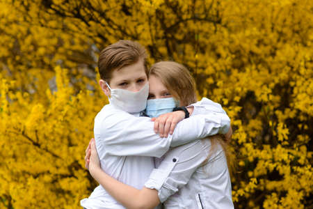 Children in a city park in a medical mask. Walking on the street during the quarantine period of the coronavirus pandemic in the Europe. Precautions and teaching childrenの写真素材