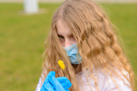 Portrait of sad caucasian child in face mask on closed playground outdoor. Coronavirus social...