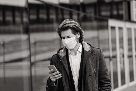 Young man in a medical mask outside, no money, poverty, hardship. Quarantine, isolation.の写真素材