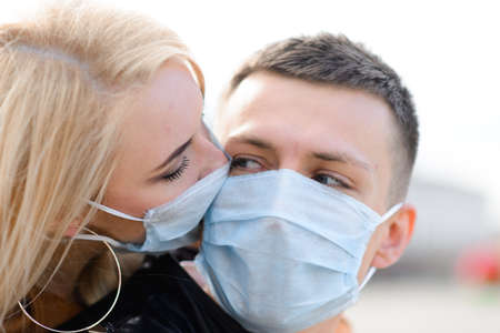 Couple wears a medical mask walking on the street of the city during the spread of news about the epidemic of coronavirus. Love story.の写真素材