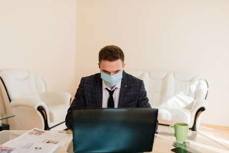 Photo of young handsoma businessman with notebook freelance job internet, want get job quarantine stay home, wear facial medical maskの写真素材
