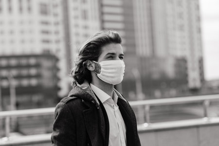 Young man in a medical mask outside, no money, crisis, poverty, hardship, isolation.