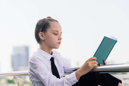 Teenager girl in summer in city park resting after school and college lessons, notebook in her hands.の写真素材