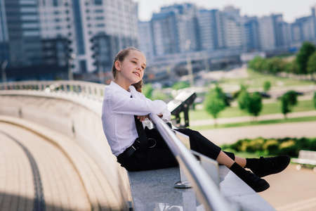 Teenager girl in summer in city park resting after school and college lessons, notebook in her hands.の写真素材