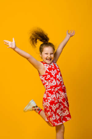 Happy carefree child emotions. Energetic joyful adorable little girl laughing at joke on yellow background in studio.の写真素材