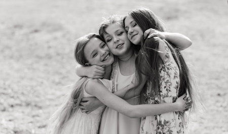Three adorable girls in dresses hold hands in a circle holding hands. Spring, garden.の写真素材