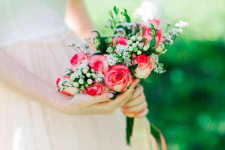 Wedding bouquet of white and red roses in bride's hands, parkの写真素材
