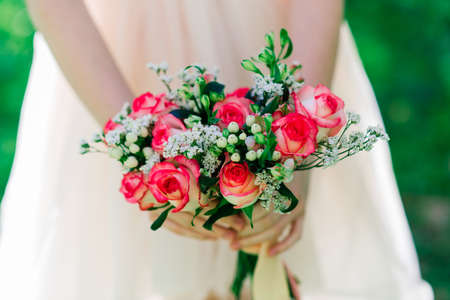 Wedding bouquet of white and red roses in bride's hands, parkの写真素材