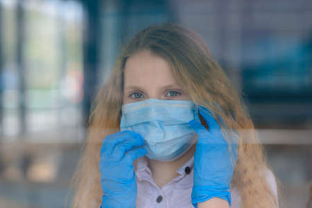 Portrait of sad caucasian child in face mask on closed playground outdoor. Coronavirus social distance and quarantine.の写真素材