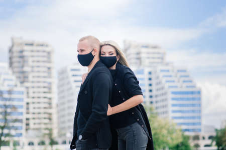 Couple wearing trendy fashionable protective masks, denim jackets, walking in empty street of European city during quarantine of coronavirus outbreak.の写真素材