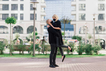 Couple wearing trendy fashionable protective masks, denim jackets, walking in empty street of European city during quarantine of coronavirus outbreak.の写真素材