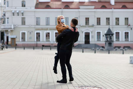 Young couple in protective medical mask on face outdoors at street. Guy and girl in virus protection.の写真素材