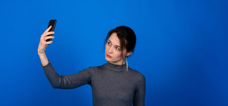 Image of a happy surprised shocked young pretty woman posing isolated over blue wall background...