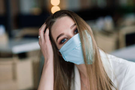Female manager in suit and medical mask works remotely on street cafe.の写真素材