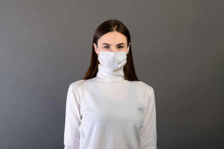 Girl in medical gloves dress protective mask on her face on studio background.の写真素材