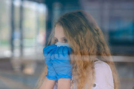 Portrait of sad caucasian child in face mask on closed playground outdoor. Coronavirus social distance.の写真素材