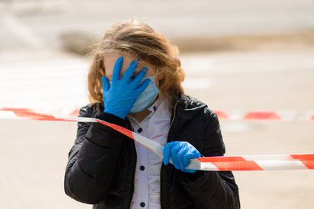 Portrait of sad caucasian child in face mask on closed playground outdoor. Coronavirus social...