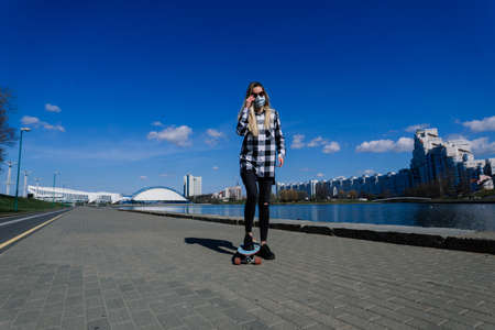 Portrait of a young female in a medical mask with longboard in the city during the quarantine periodの写真素材