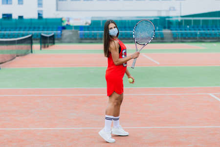 Portrait of tennis player girl holding racket outside with protective maskの写真素材