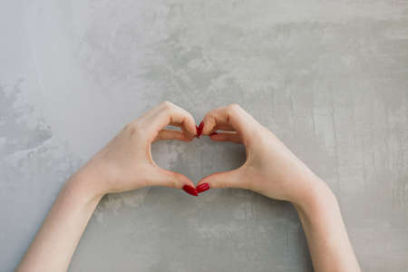 Isolated woman's hands with red nails in front of a grey wallの写真素材