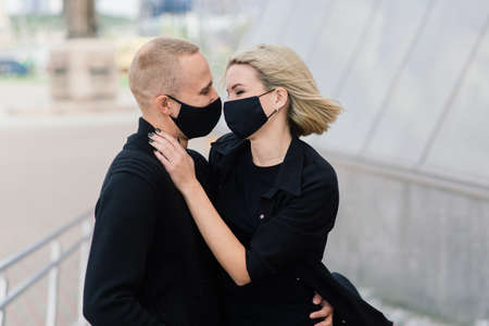 Couple wearing fashionable protective masks, walking in empty street of the city during quarantine.の写真素材