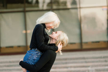 Two young females walking smiling embracing and kissing outdoorの写真素材