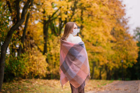 A young woman protecting from corona virus when walking in park. Autumn background.の写真素材