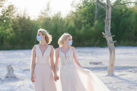 Lesbian couple wedding on white sand, wear masks to prevent epidemic COVID-19の写真素材