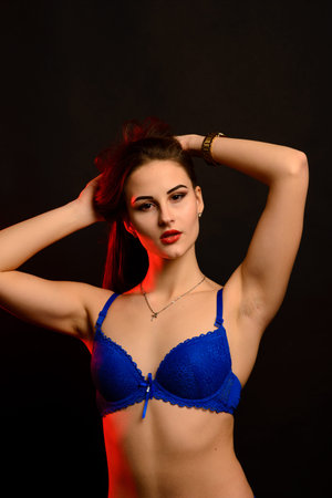 Beautiful sexy woman in blue underwear on a dark background, perfect female body, studio shot