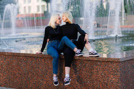 Two young females walking smiling embracing and kissing outdoorの写真素材