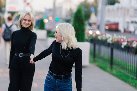 Two young females walking smiling embracing and kissing outdoor