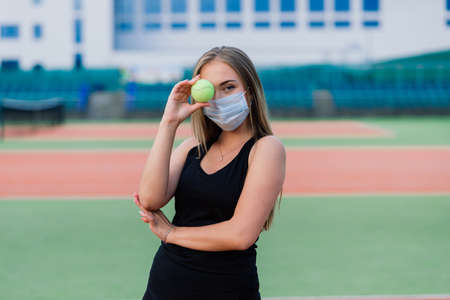 Female tennis player playing with protective mask on courtの写真素材