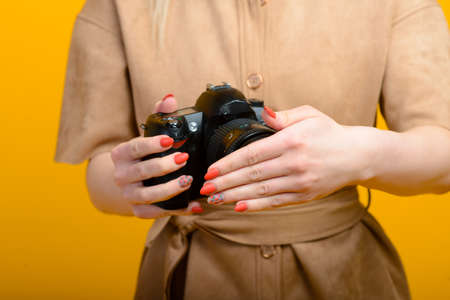 Image of hands with digital photo camera on yellow backgroundの写真素材