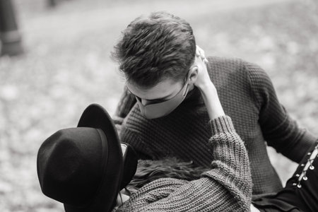 Young red haired woman puts on a face mask while walking with young man in autumn park.
