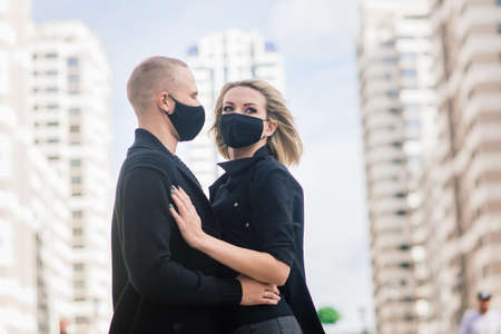 Couple wearing fashionable protective masks, walking in empty street of the city during quarantine.の写真素材