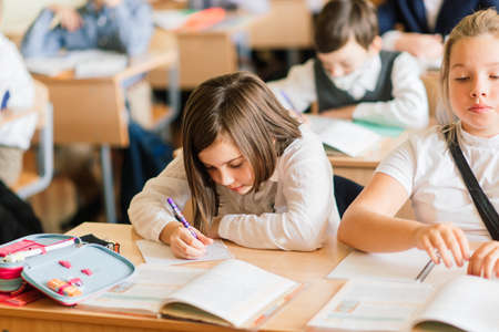 Minsk, Belarus - 09.01.2020. Elementary schoolchildren writing in books in classroomのeditorial素材