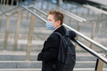 Schoolboy walks out of school wearing protective mask in the city