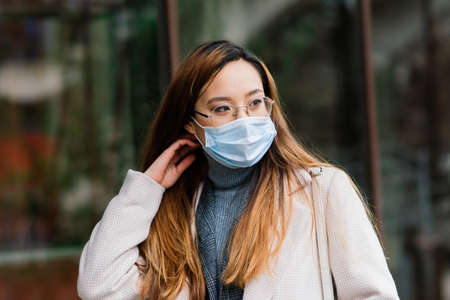 Young asian woman with surgical mask face protection. She commutes between home and workplace in cityの写真素材