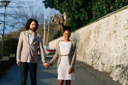 Milan, Italy - 02.04.2020. Young adult interracial couple on a beach, Caucasian man and African American female in casual clothes enjoying summer day on a sea shoreのeditorial素材