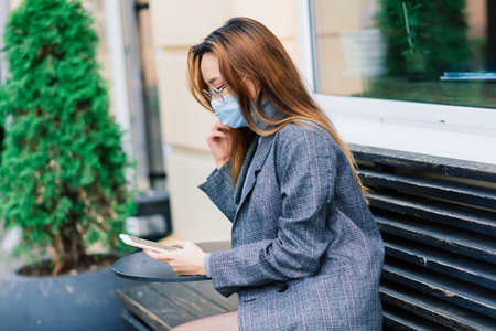 Young fsian woman wearing face mask is standing at a domestic street. Concept new normal of commuters after covid-19 epidemicの写真素材