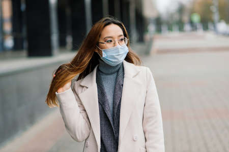 Young fsian woman wearing face mask is standing at a domestic street. Concept new normal of commuters after covid-19 epidemicの写真素材
