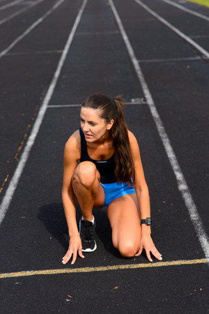 Healthy young woman warming up stretching her arms in the stadium outdoor, jogging session in park.