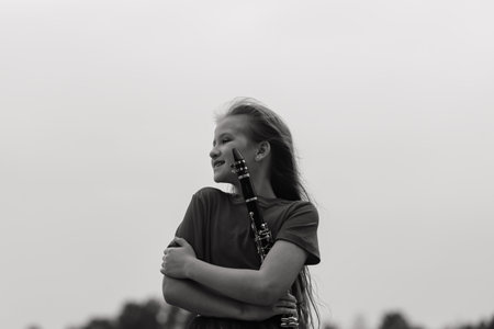 Young attractive girl playing clarinet in fall parkの写真素材