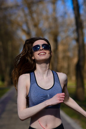 A close up of attractive young woman running, doing fitness outdoorsの写真素材