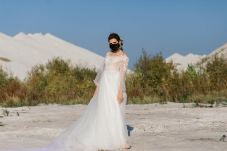 Bride in wedding dress with medical mask at coronavirus covid quarantine period.