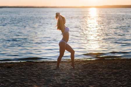 Minsk, Belarus - 07.08.2020. Caucasian fit woman with sport body posing on beach at sunset time. Weight loss by summer.のeditorial素材