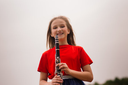 Young attractive girl playing clarinet in fall parkの写真素材