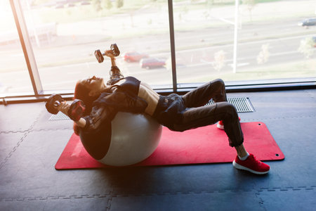 Athletic girl in sportswear performs exercises with a barbell, dumbbells. Fitness, workout, healthy lifestyleの写真素材